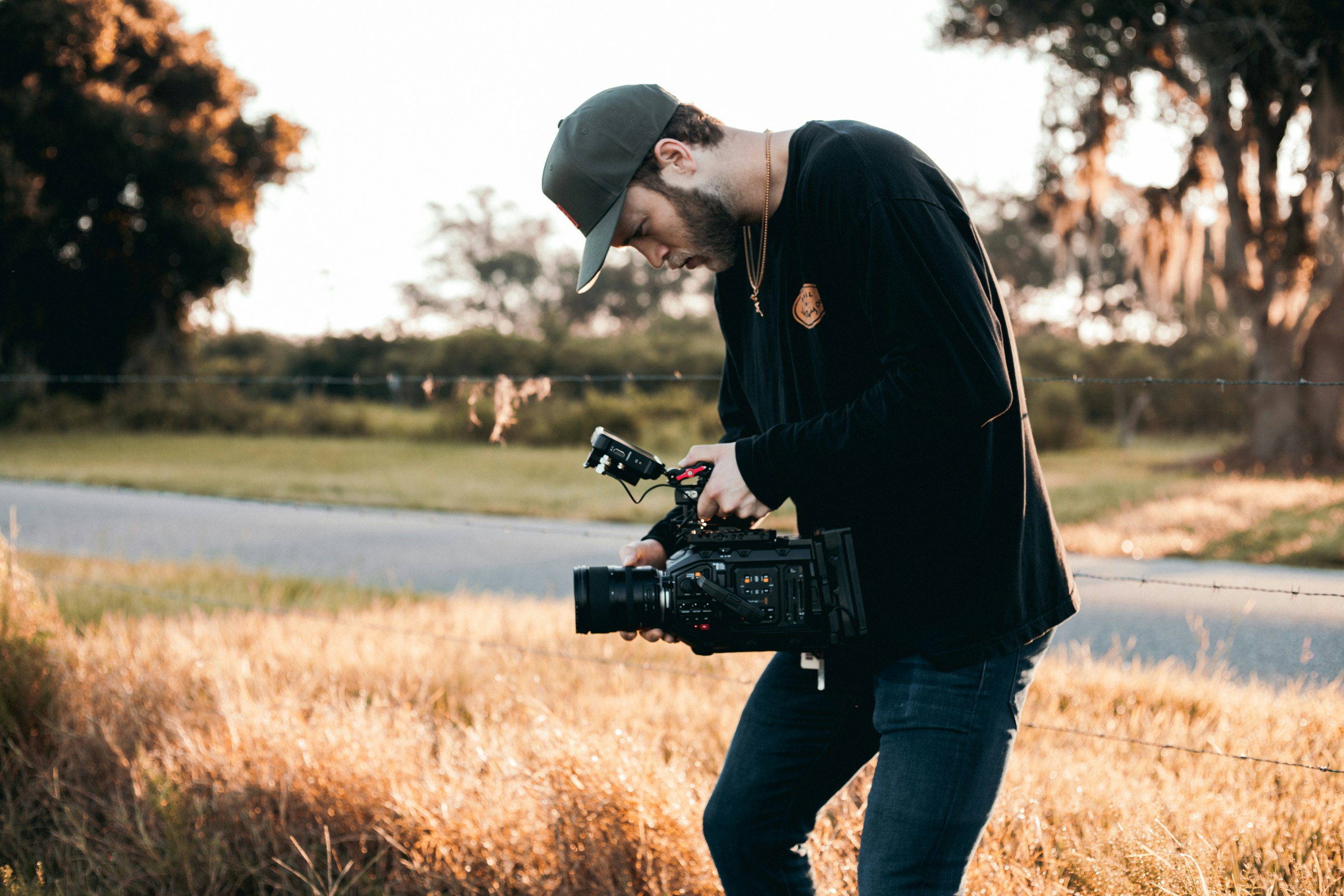 man in black jacket and blue denim jeans holding black dslr camera